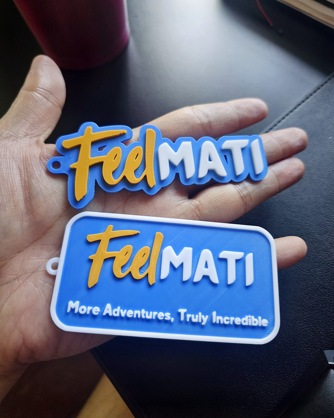 A tray of blue tourism-branded keychains and plaques next to packaged paddle-shaped keychains on a workbench.